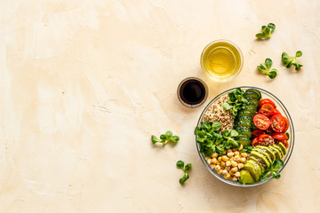 Healhty vegan lunch bowl. Avocado, quinoa, sweet potato, tomato, spinach and chickpeas vegetables salad on brown table. Top view