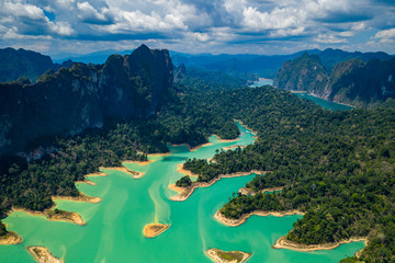 Aerial drone view looking down onto tiny, jungle covered islands in a huge lake surrounded by...