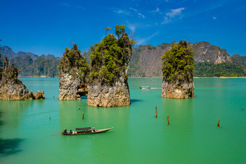 Fototapeta premium Aerial drone view of longtail boats around spectacular limestone fingers and karsts on a huge lake surrounded by jungle