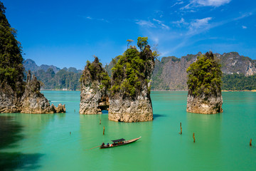 Aerial drone view of longtail boats around spectacular limestone fingers and karsts on a huge lake surrounded by jungle