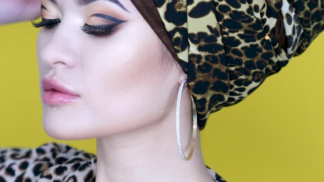 Bold and beautiful young woman in a turban with a leopard print, ethnic trends, portrait on a bright yellow background