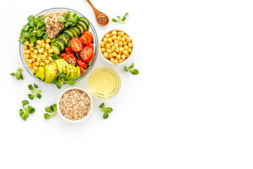 Healhty vegan lunch bowl. Avocado, quinoa, sweet potato, tomato, spinach and chickpeas vegetables salad on white table. Top view