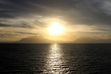 evocative image of sunset over the sea with headland silhouette in the background