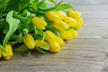 Blooming spring bouquet of yellow tulip flowers on wooden background. Copy space.