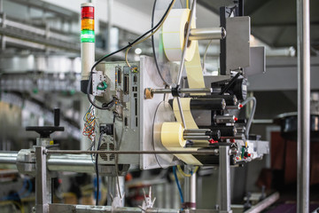 Industrial equipment on the conveyor for the production of juice in bottles, applying labels.