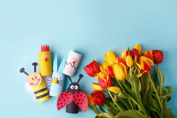 Springtime season greeting card - happy easter concept - multicolored tulips, eggs, decor from toilet roll tube on blue background, copy space, celebrate banner