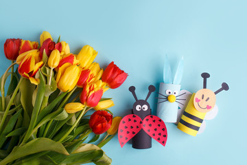 Happy easter spring toy collection and fresh flowers on blue background, kids holiday party concept background. Paper crafts, DIY. creative idea from toilet roll. reuse, recycle