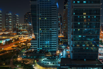 Fototapeta na wymiar Modern city buildings at night. Typical Dubai high-rise constructions.