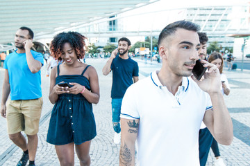 Diverse group of people excited with their smartphones. Mix raced men and women walking outside, talking on cells, using mobile phones. Mobile communication concept