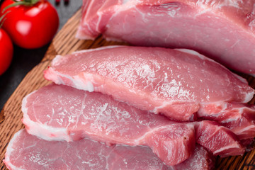 Fresh pieces pork ready to cook on a dark background in the kitchen