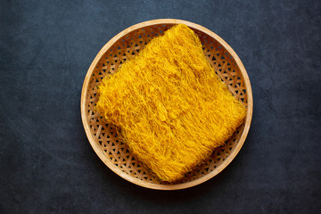 Rice noodles made with carrot juice on dark background.