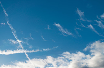 Blauer Himmel mit ein paar weißen Wolken und Kondensstreifen