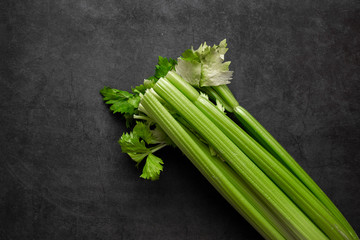 Fresh green celery stems on dark background.