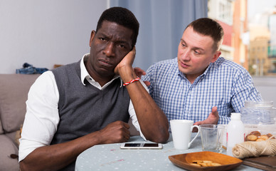 Unhappy male  after conflict, friend tries reconcile