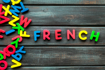 Learn French. Concept with letters on dark wooden background top-down copy space