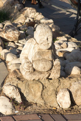figurine of a small fat man in a sitting position as an element of small architecture at the sidewalk