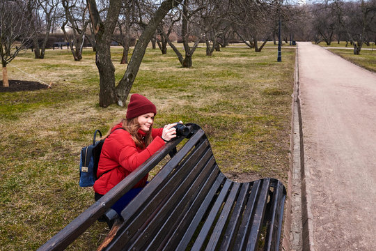  girl in a red jacket takes pictures on camera in the park in spring