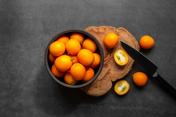 Top view of fresh kumquats on dark background. Some kumquats is cutted