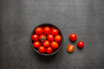 Top view of fresh red cherry tomatoes (grape tomatoes ) on dark background. Some cherry tomatoes is cutted