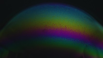 Obraz na płótnie Canvas Rainbow soap bubble on a dark background. Close-up of colorful surface