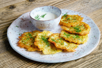 marrow fritters with dill and yogurt on fleck ceramic plate and wooden background