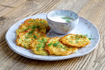 squash fritters with dill and yogurt on fleck ceramic plate and wooden background
