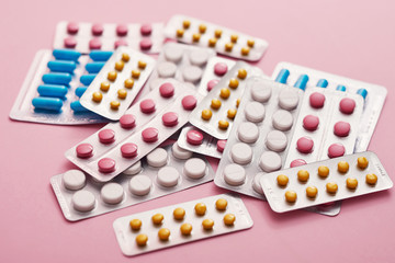 Assorted pharmaceutical medicine pills, tablets and capsules on pink background. Heap of various pills. Coronovirus, quarantine, epidemic, pandemic, flu, cold,illness. Medicine concept and health
