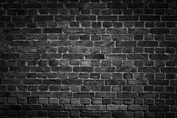 Fototapeta na wymiar An old black bricks wall surface abstract pattern background. Background of old vintage brick wall with vignetting.