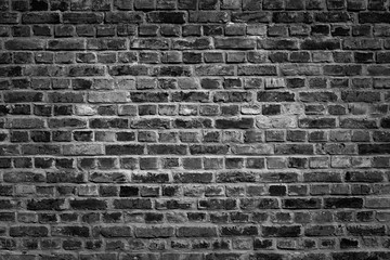 An old black bricks wall surface abstract pattern background. Background of old vintage brick wall with vignetting.
