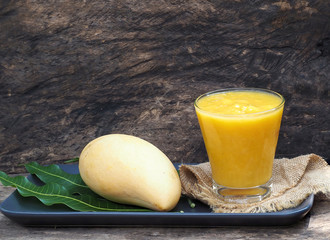 Mango smoothie in glass with slices of mango fruit on wooden background from the top view. drink for healthy high protein the taste yummy