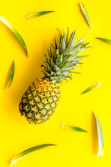 Pineapple on bright yellow background with leaves top-down