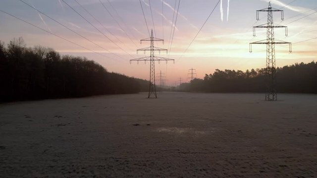 Power lines in morning sunrise light, public infrastructure for electricity distribution across countryside environment