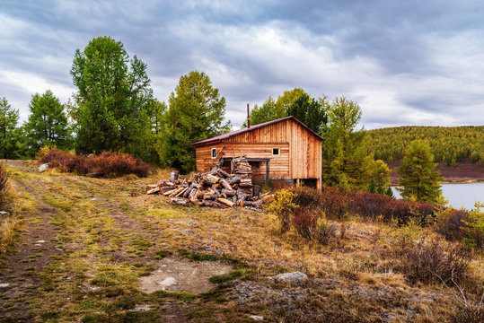 Wooden bath with a stack of firewood on the lake Uzunkel. Ulagansky District, Altai Republic, Russia