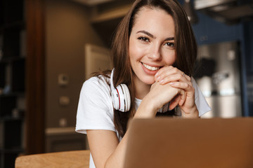 Image of joyful beautiful woman smiling and working with laptop