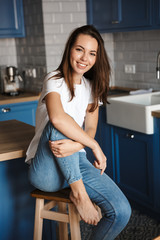 Image of cheerful beautiful woman smiling while sitting