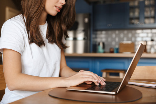 Cropped image of young brunette woman typing on laptop
