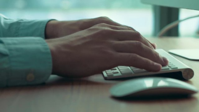 Close-up shot of male code developer hands typing, working behind office table with laptop at modern coworking space.