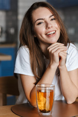 Image of cheerful beautiful woman laughing and drinking tea