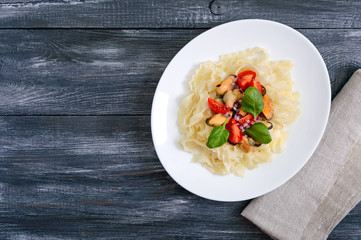 Pasta with mussels, tomatoes on a white plate. Top view.
