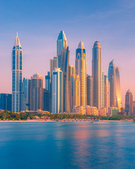 Sunset view of high rise buildings and skyscrapers in Dubai Marina during golden hour