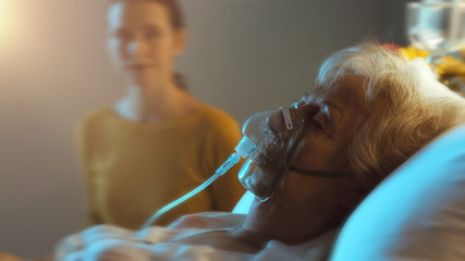 Woman assisting a senior patient with oxygen mask