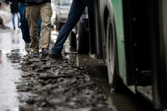 People Are Standing At A Bus Stop, Getting On A Bus Stepping Over Uncleared Snow And Mud, Special Services Do Not Clean The City