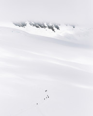 Landscape view of mountain climbers & hikers climbing and walking up theSiss Alps fully covered with ice