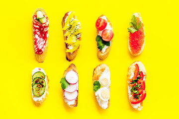 Fototapeta premium Sandwiches assorti pattern on yellow background top-down