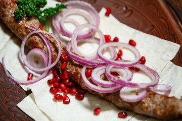 A dish cooked on the kebab grill. Georgian dishes. Garnished with onions and pomegranate seeds