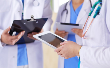 Doctors using a tablet in hospital standing in office