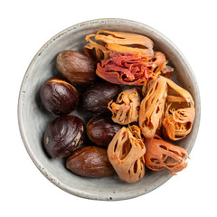 Dried organic mace or jayitri and nutmeg in ceramic bowl isolated on white background. Top view.