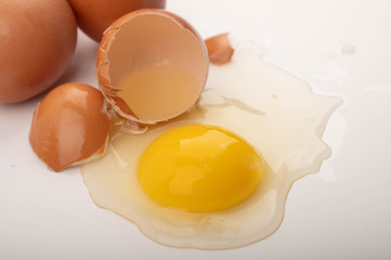 Broken chicken egg and eggs scattered on a white background. Close up.
