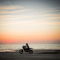 Fototapeta na wymiar Masirah Island, Oman, January 1, 2020: Man on a motorcycle on the beach at sunset