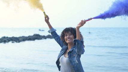 Holiday concept. Beautiful girl playing fun colored smoke on the beach. 4k Resolution.